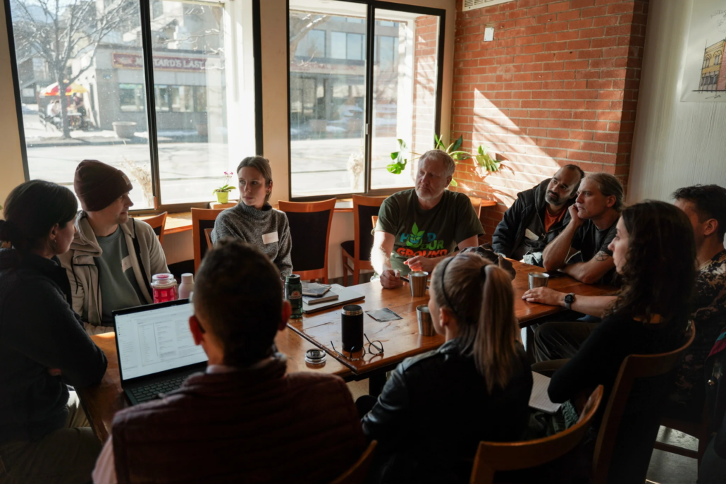 Intimate roundtable discussion at Boulder Riverside with natural light, exposed brick, and street views