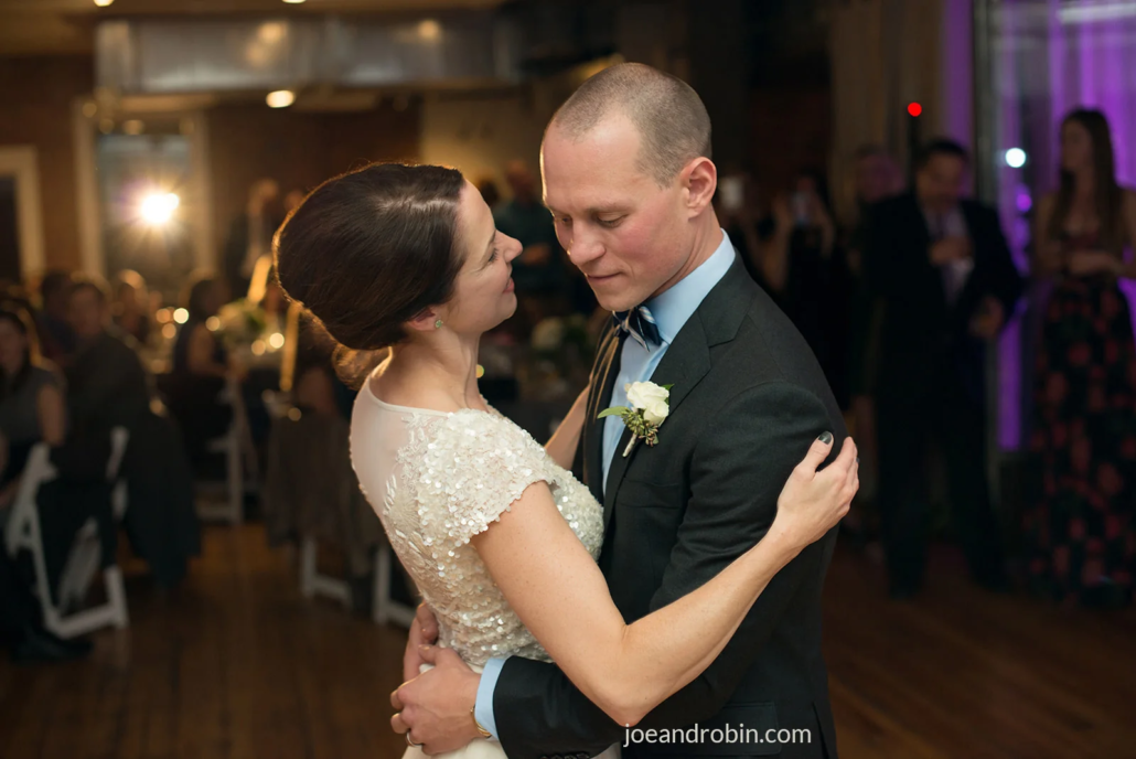 Couple sharing their first dance at a Boulder Riverside wedding reception with guests in the background