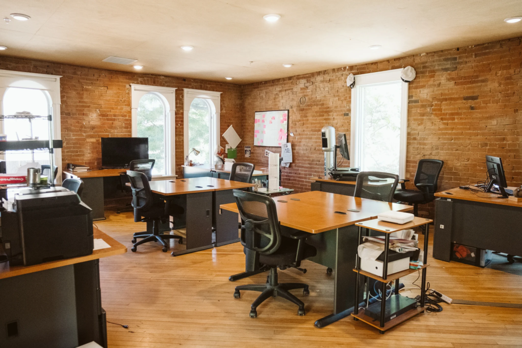 Open-plan coworking office at Boulder Riverside with arched windows, exposed brick, and multiple workstations